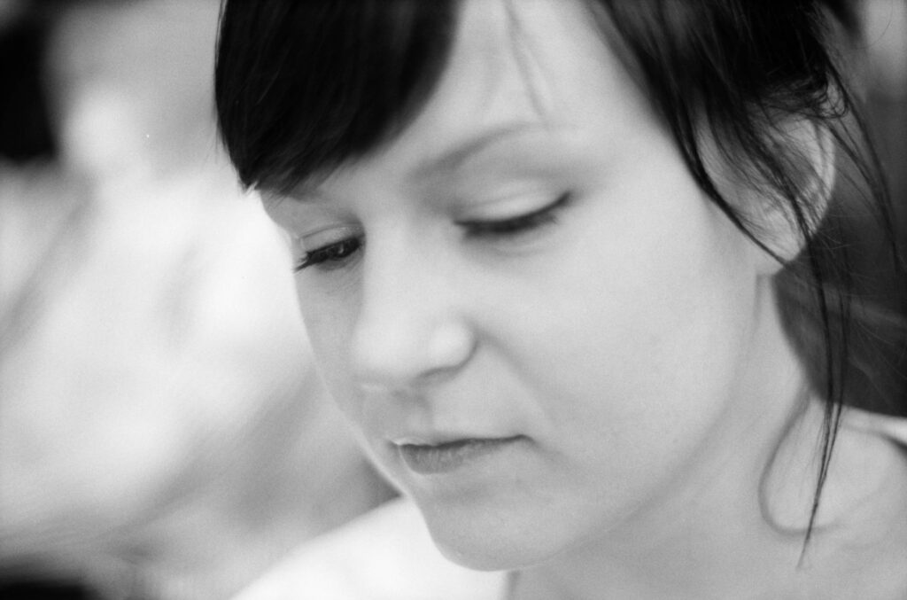 Close-up black and white photograph showing the curve of a person's neck and shoulder with soft strands of hair, evoking stillness and introspection.
